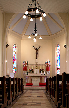 View inside the church of Rambucourt, from the entrance, showing the altar, statues and stained glass.
