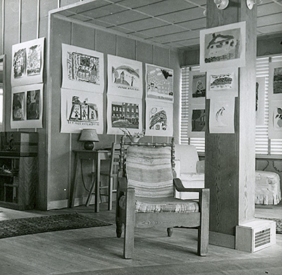 Children's artwork exhibit where a corner of the living room walls are covered with children's artwork.