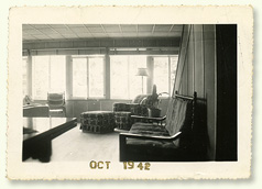 View of the ground floor where we can see chairs against the wall and window in the background that are bathed in light.