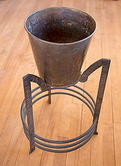Cast iron plant support with a base that reminds of a grasshopper's legs.