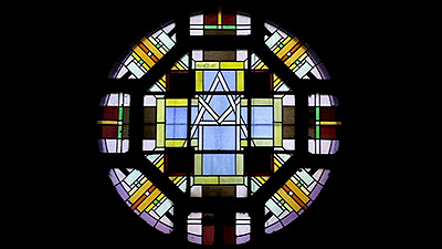 Scene from the video showing a circular stained-glass window made of abstract geometric shapes.