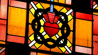 Scene from the video showing a detail of a stained-glass window representation of a Sacred Heart.