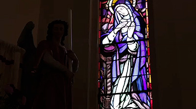 Scene from the video showing a stained glass window representation of the Virgin Mary.