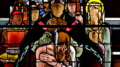 Scene from the video showing a detail of a stained-glass window representing a biblical scene.