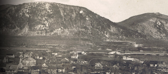 View of St-Hilaire. We can see the frozen river, the village, fields and the mountain.